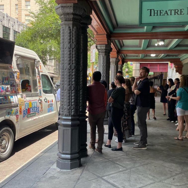 Crowd lines up at Frosty Brothers ice cream truck outside a historic downtown San Antonio theatre during a special event.