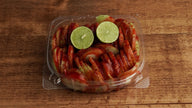 Prepared cucumber snack with fresh lime, chamoy, Tajín, and chili seasoning made fresh at Frosty Brothers Shaved Ice & Snacks.