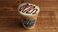 Creamy Mexican street corn in a cup with sweet corn, mayonnaise, butter, cotija cheese, and hot sauce, freshly prepared at Frosty Brothers Shaved Ice & Snacks in San Antonio, Texas.