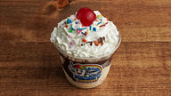 Classic vanilla ice cream sundae topped with chocolate syrup, whipped cream, rainbow sprinkles, and a cherry, freshly made at Frosty Brothers Shaved Ice & Snacks in San Antonio, Texas.
