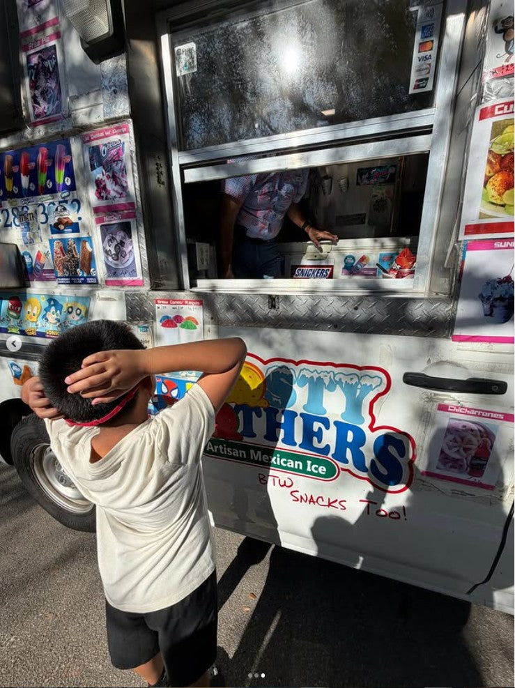 Young customer choosing frozen treats from the Frosty Brothers Ice Cream Truck during a birthday party in San Antonio, Texas.