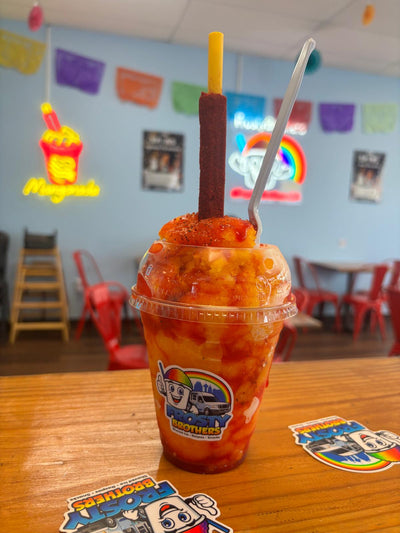 Authentic mangonada made with mango shaved ice, chamoy, Tajín, fresh mango, and a tamarind candy straw at Frosty Brothers shop in San Antonio.
