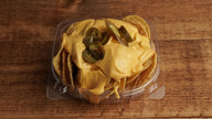Crispy Nacho tortilla chips topped with warm nacho cheese and sliced jalapeños, freshly prepared at Frosty Brothers Shaved Ice & Snacks in San Antonio, Texas.