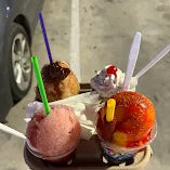 Customer favorites at Frosty Brothers featuring a spicy mangonada, fluffy shaved ice, and a classic ice cream sundae served on a tray. Freshly prepared desserts and frozen treats available at our San Antonio shaved ice shop and ice cream truck.