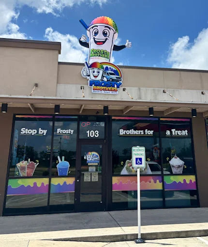 Front entrance of Frosty Brothers Shaved Ice & Snacks in San Antonio, Texas, featuring colorful storefront graphics, outdoor signage, and serving fresh shaved ice, raspas, fruit cups, aguas frescas, and Mexican snacks.