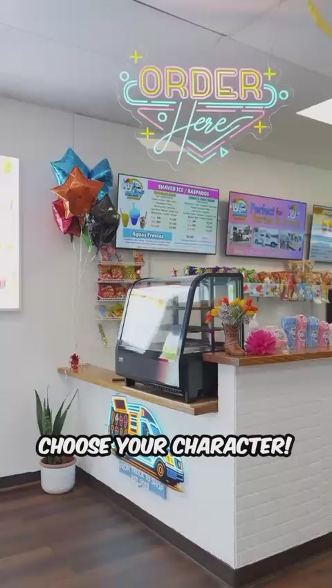 Video tour of the Frosty Brothers shaved ice shop in San Antonio featuring the ordering counter, colorful menu boards, neon "Order Here" sign, fresh fruit station, and family-friendly atmosphere serving raspas, mangonadas, aguas frescas, snacks, and desserts.